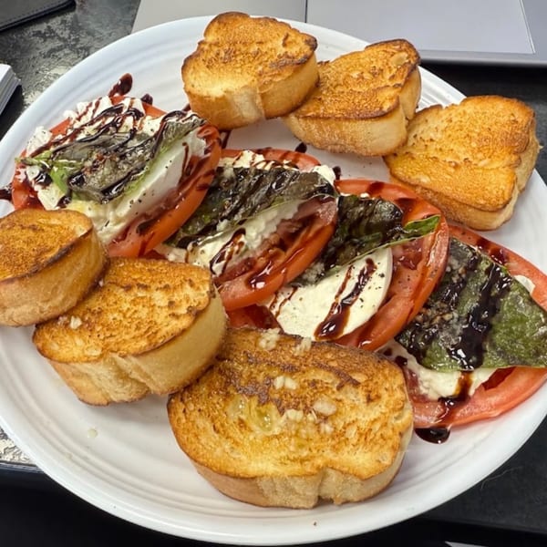 Pizzany's Pizzeria Caprese salad with sliced tomatoes, mozzarella, basil, balsamic glaze, and toasted bread.