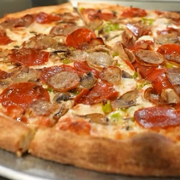 A freshly baked Pizzany's Pizzeria pizza with pepperoni, sausage, mushrooms, and green peppers.