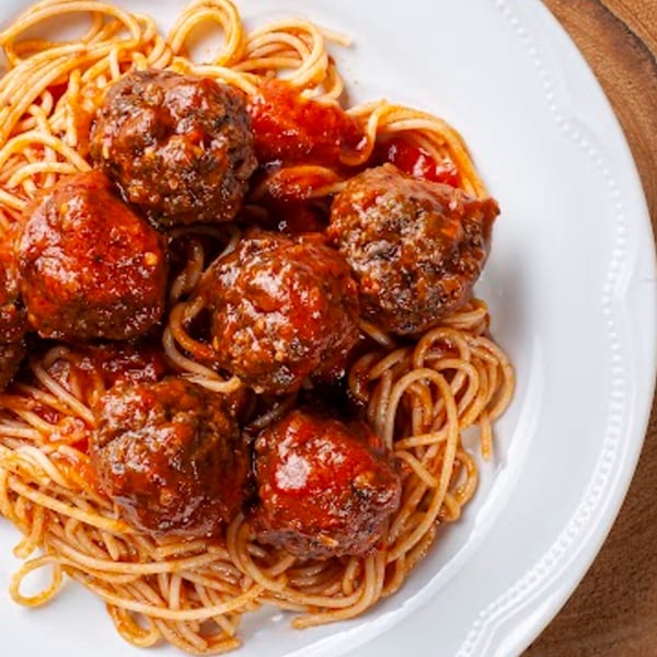 Spaghetti and meatballs with red sauce on a white plate, a classic Italian-American dish from Pizzany's Pizzeria.