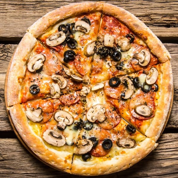 Pizzany's Pizzeria pizza with mushrooms, black olives, and pepperoni on a wooden table.