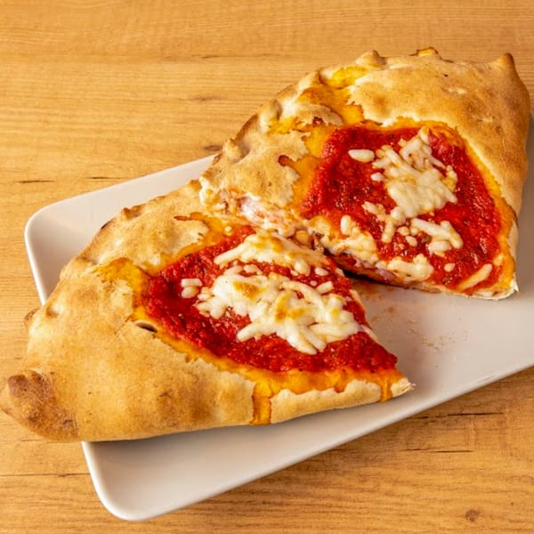 Two slices of Pizzany's calzone, filled with red sauce and melted cheese, on a white plate.